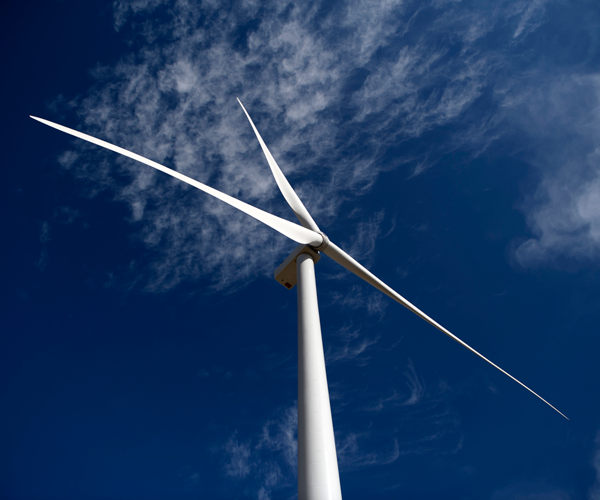 A single wind turbine with a deep blue sky background
