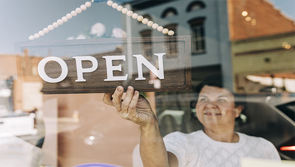 Woman changing business door sign to open.