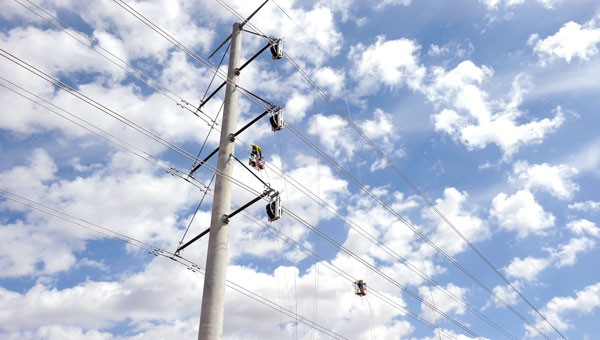 NextEra employees in the air working on transmission lines